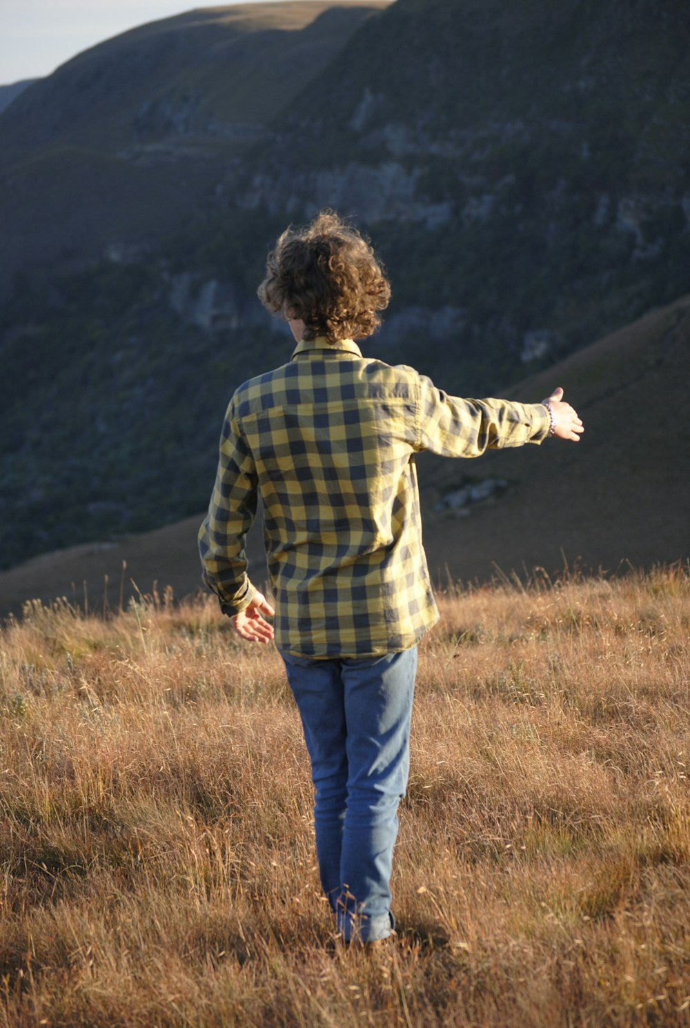 man in blue and white plaid dress shirt standing on brown grass field during daytime