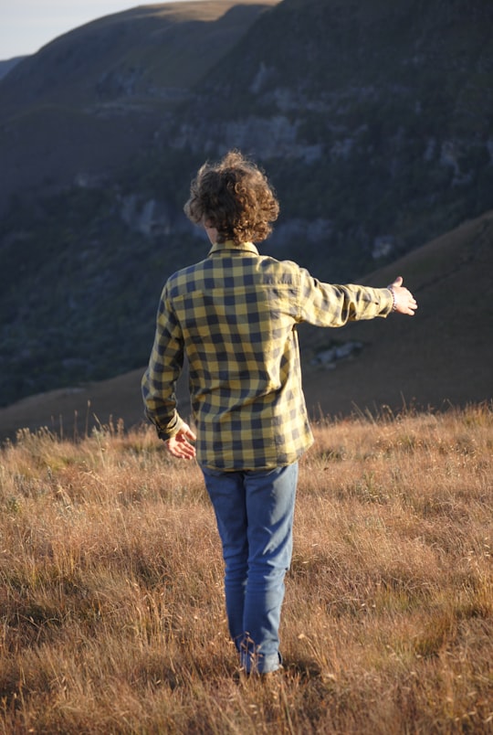 man in blue and white plaid dress shirt standing on brown grass field during daytime in KwaZulu-Natal South Africa