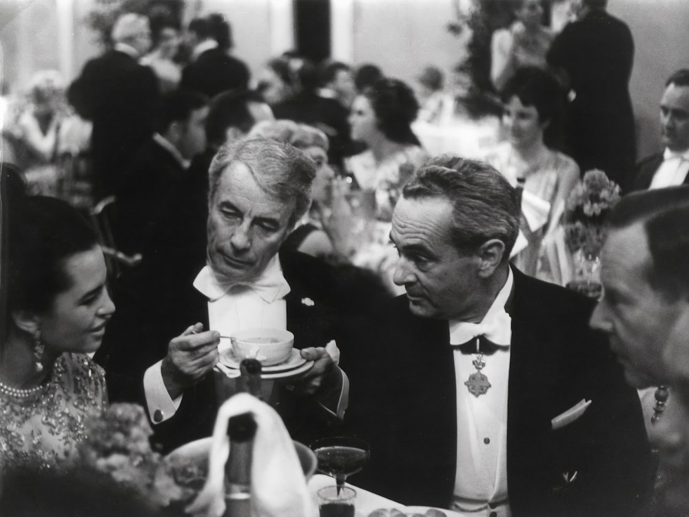 man in black suit jacket holding woman in white dress