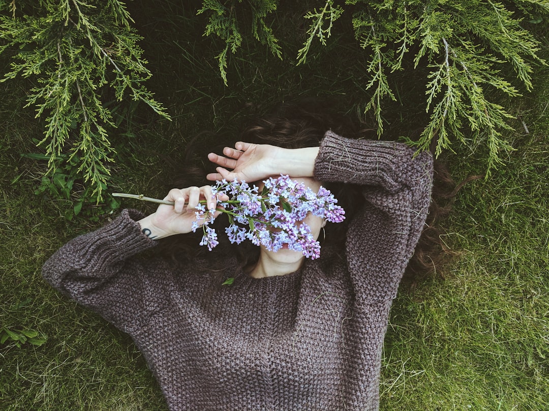 woman in gray sweater holding white and purple flowers
