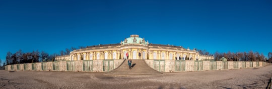 people walking on pathway near white concrete building during daytime in Potsdam Germany