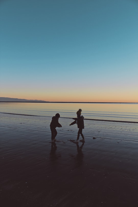 man and woman walking on beach during sunset in Nelson New Zealand