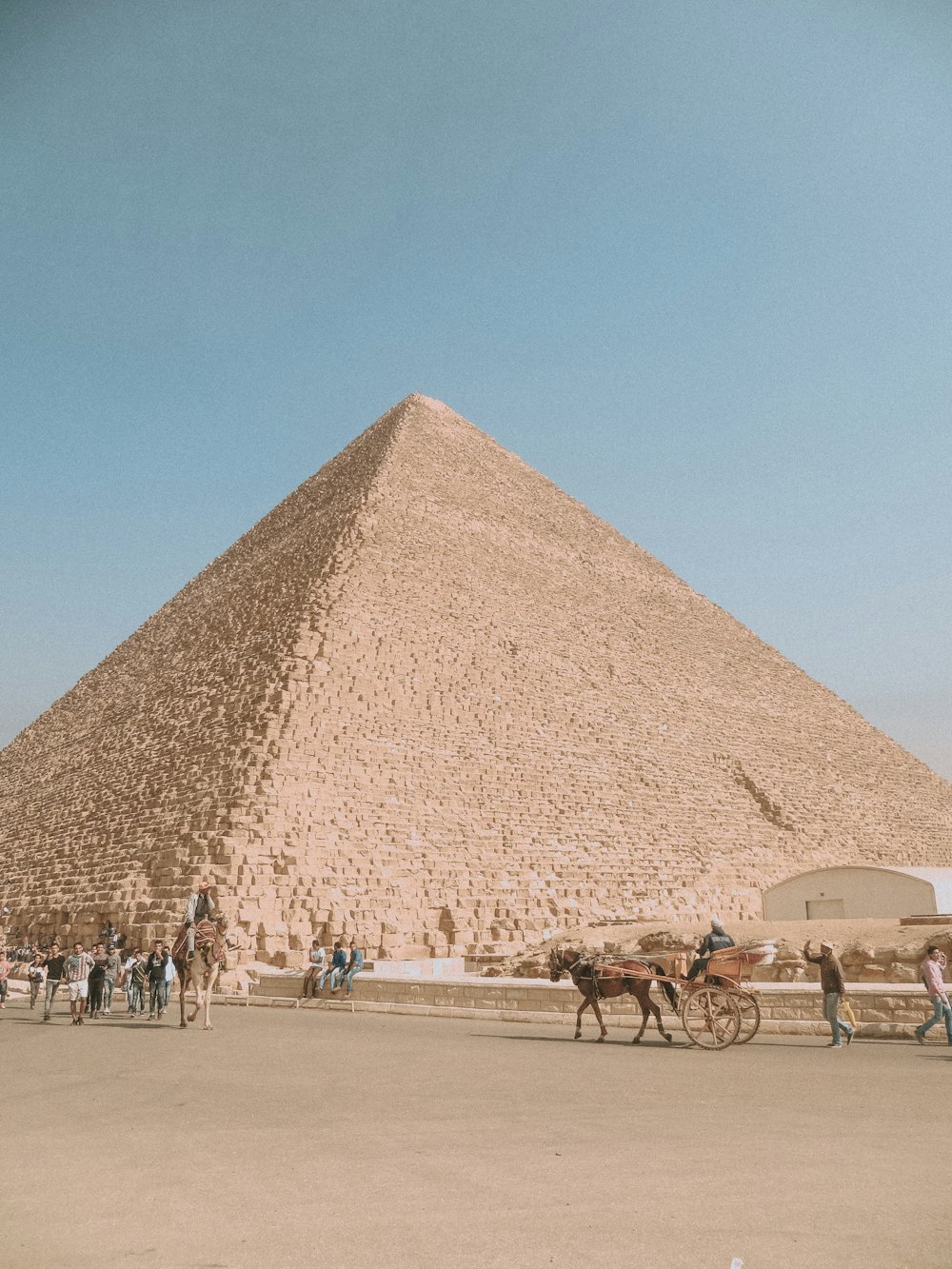 people walking on brown sand near pyramid under blue sky during daytime