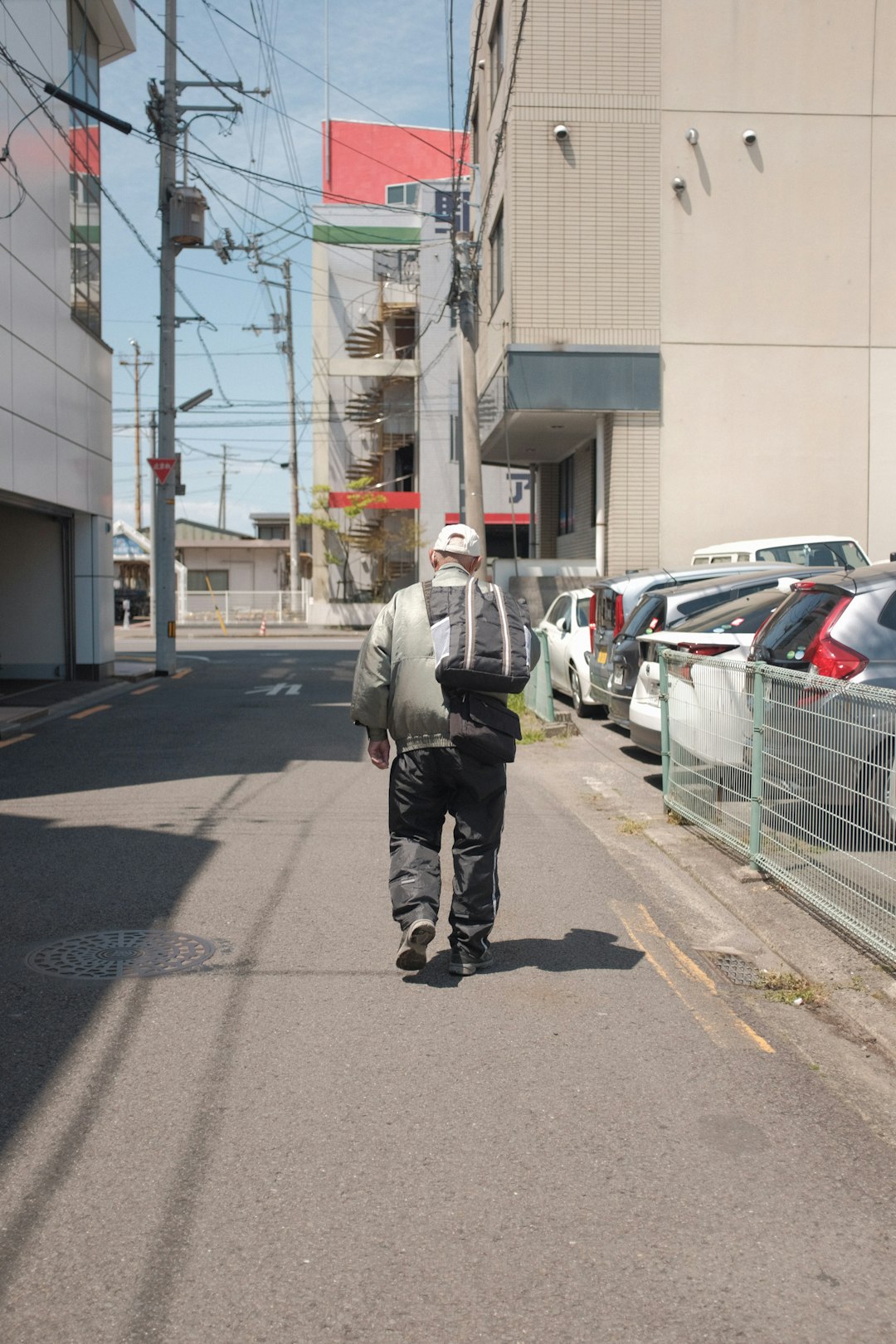 man in gray jacket walking on sidewalk during daytime