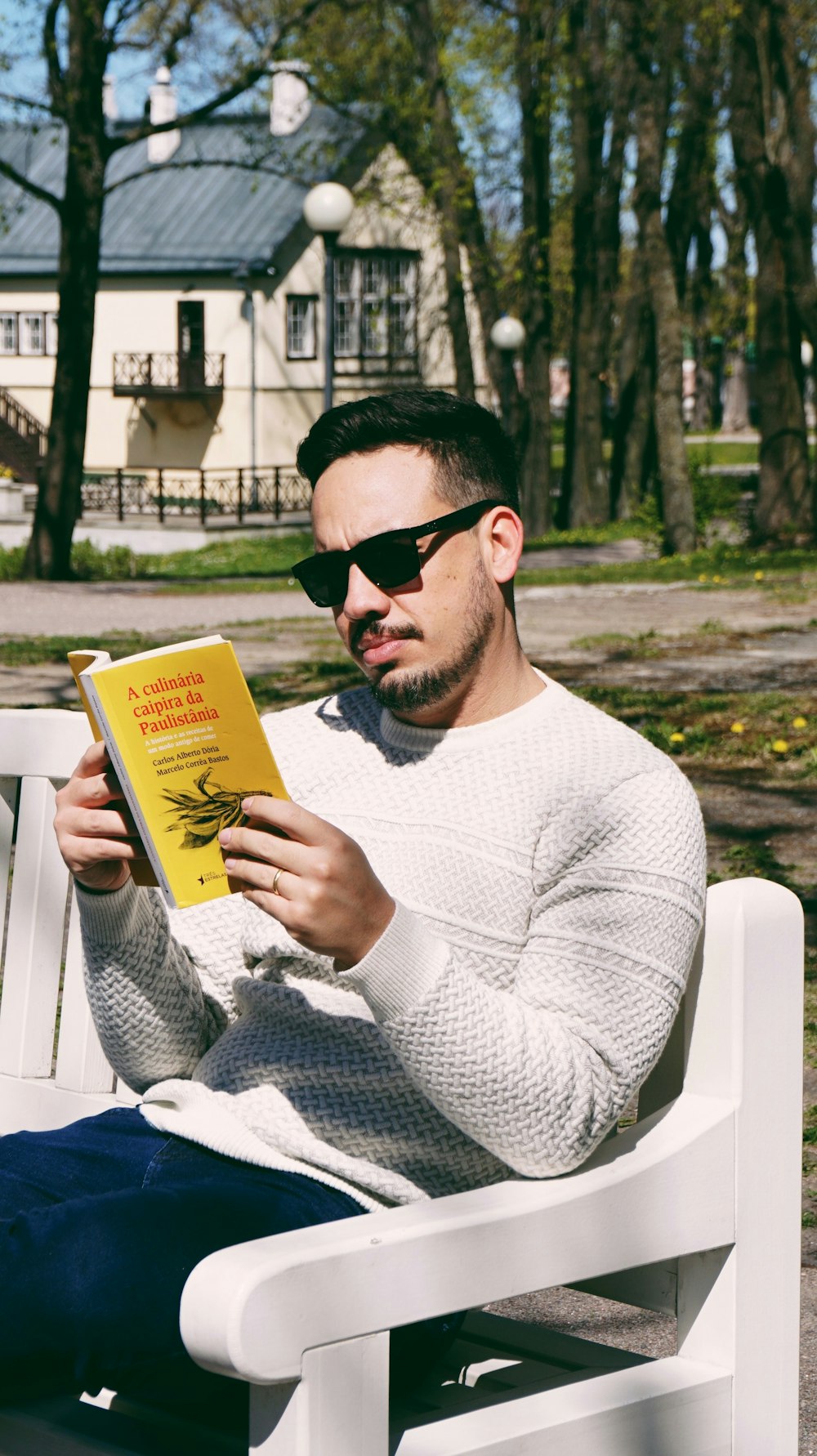 man in white sweater holding yellow book