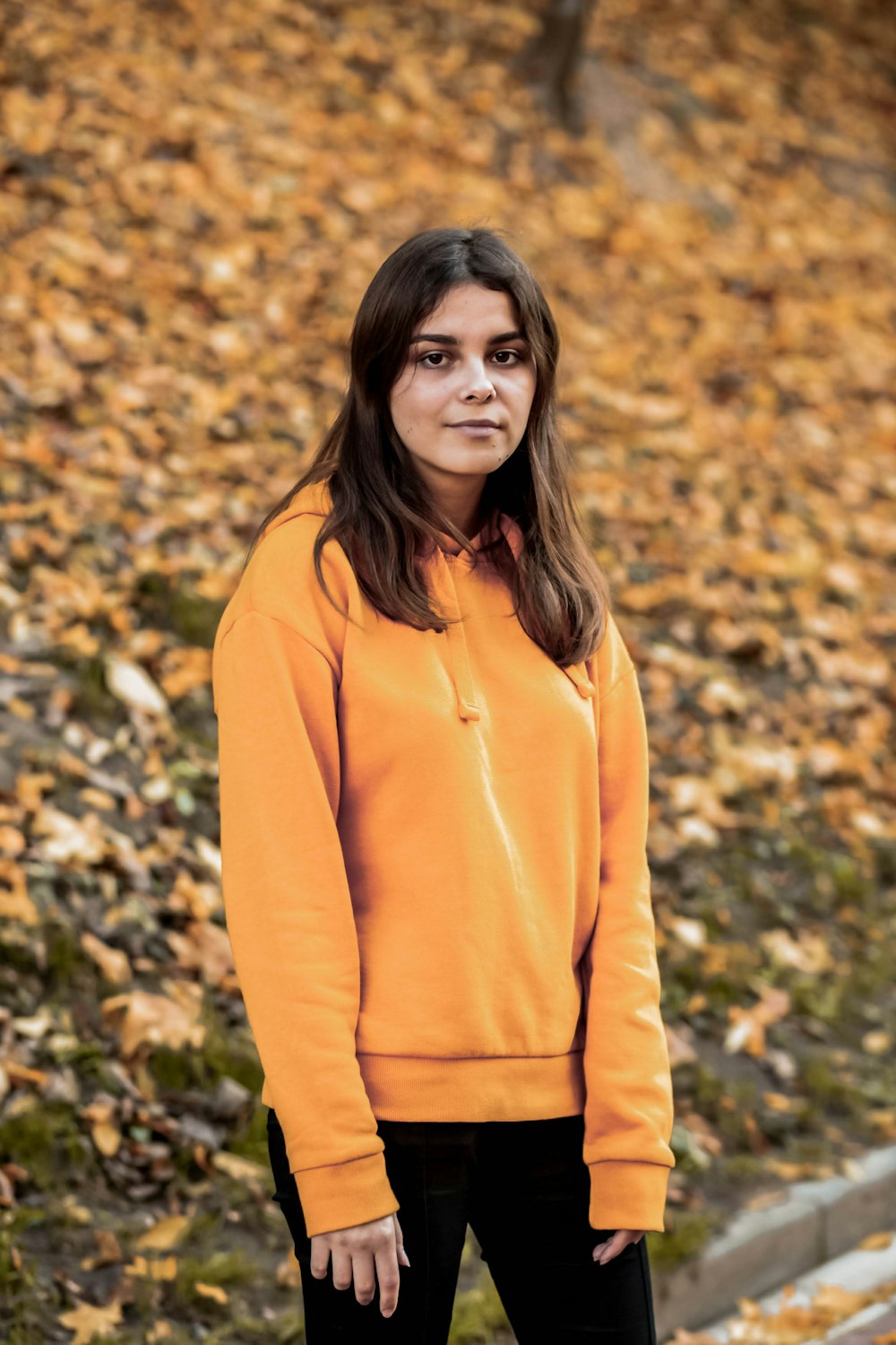 woman in brown long sleeve shirt standing on brown leaves during daytime