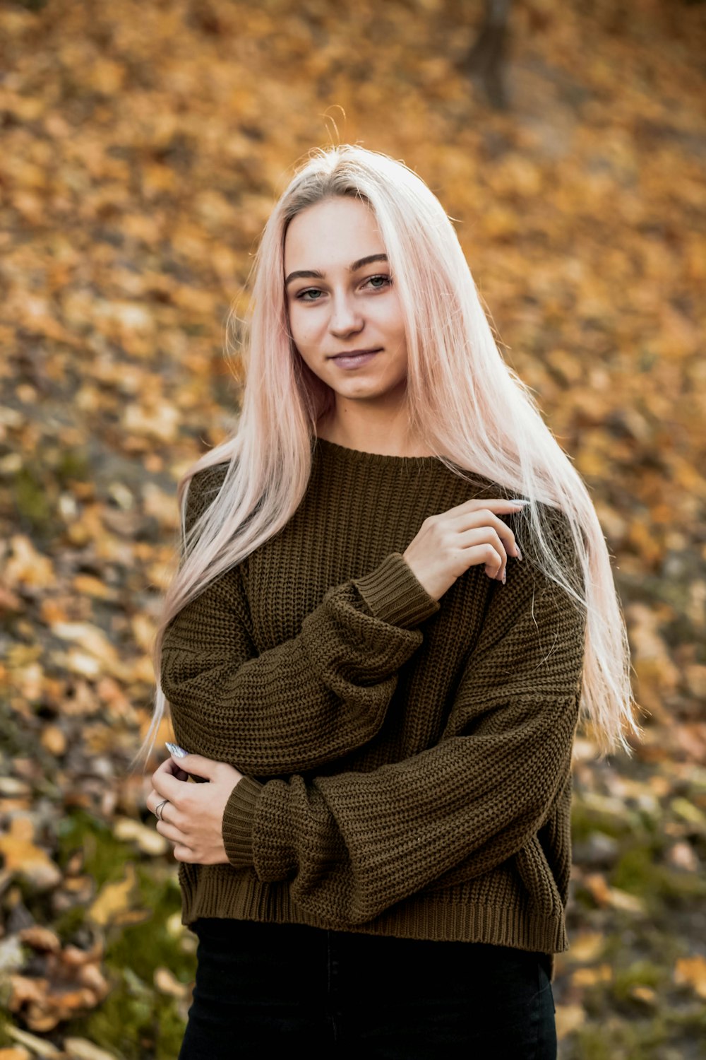 woman in brown long sleeve shirt standing on brown leaves during daytime