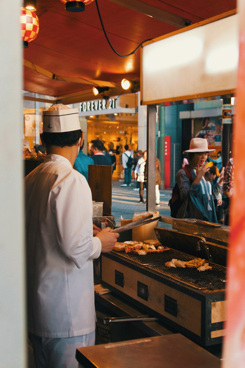 man in white dress shirt standing in front of food stall