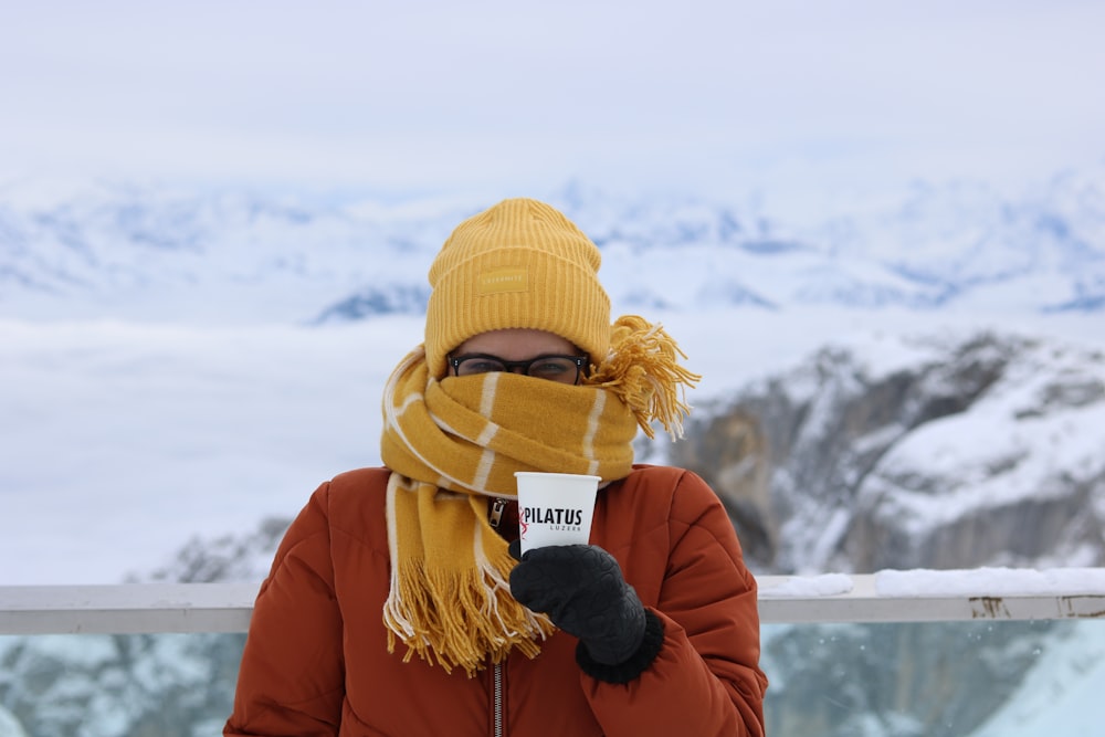 woman in brown knit cap and red jacket standing on snow covered ground during daytime