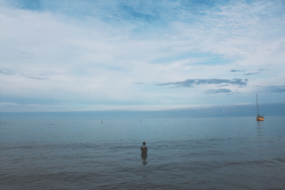 person standing on sea shore under blue sky during daytime