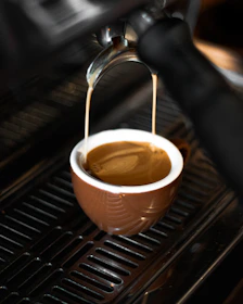 A barista pouring a rich espresso shot from freshly ground Arabica beans.