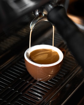 Close-up of a rich espresso pouring from a polished portafilter with steam rising gently.