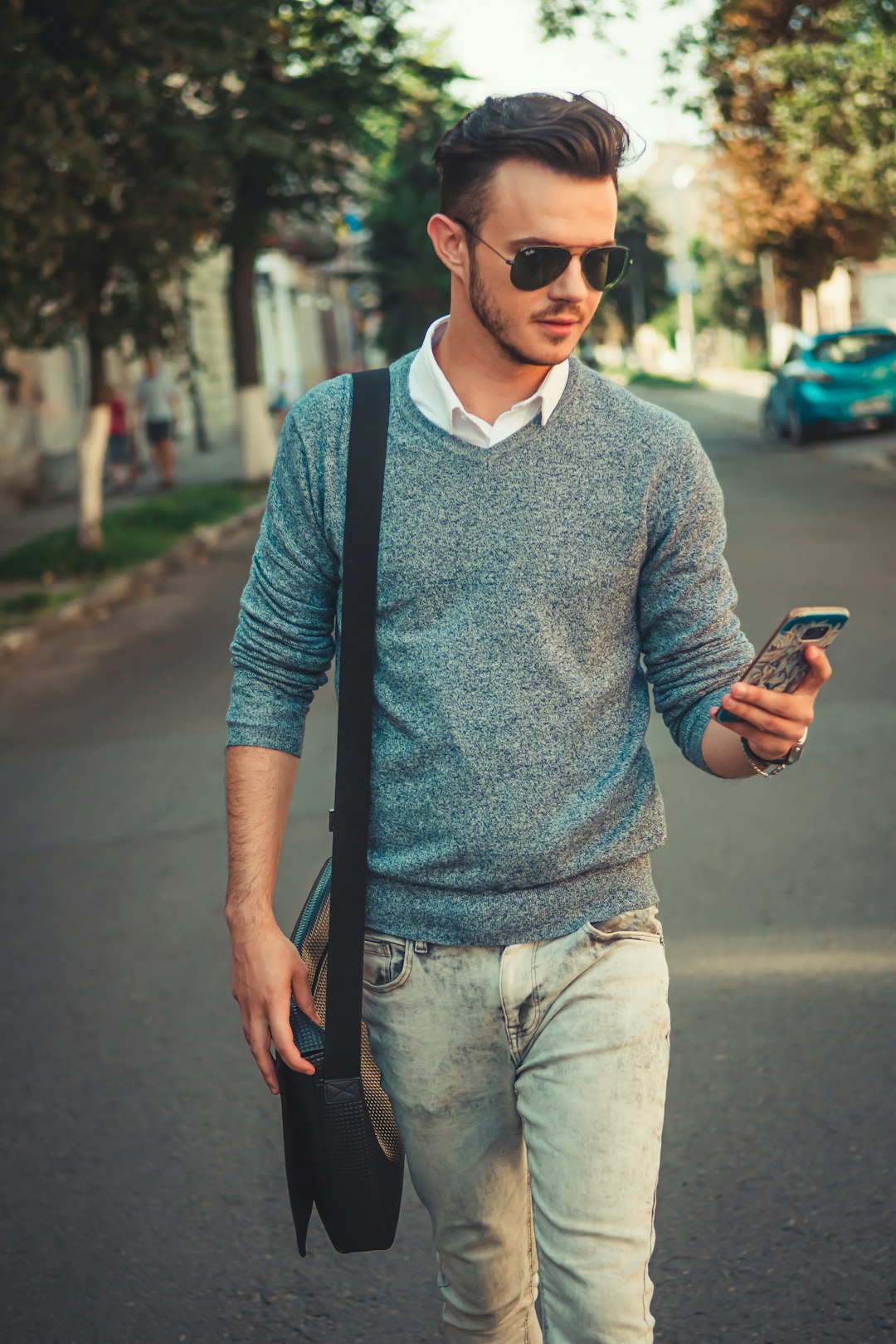 man in blue and gray polo shirt holding black smartphone