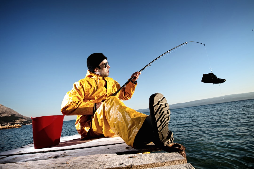 man in yellow jacket and black and white adidas cap holding black fishing rod