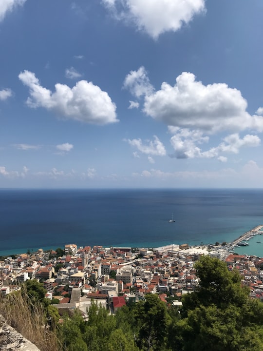 city buildings near sea under blue and white cloudy sky during daytime in Zakynthos Greece