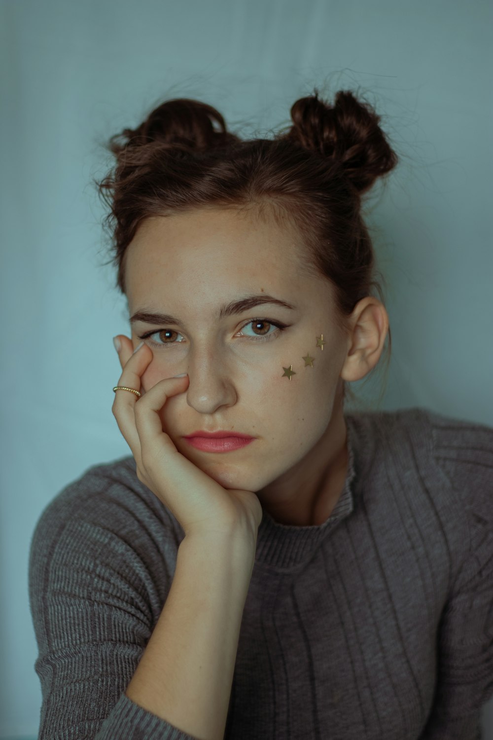 woman in gray sweater with hand on face