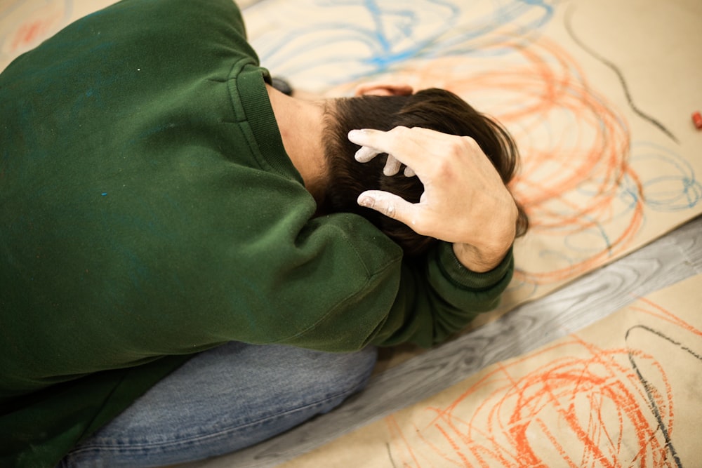 man in green sweater lying on bed