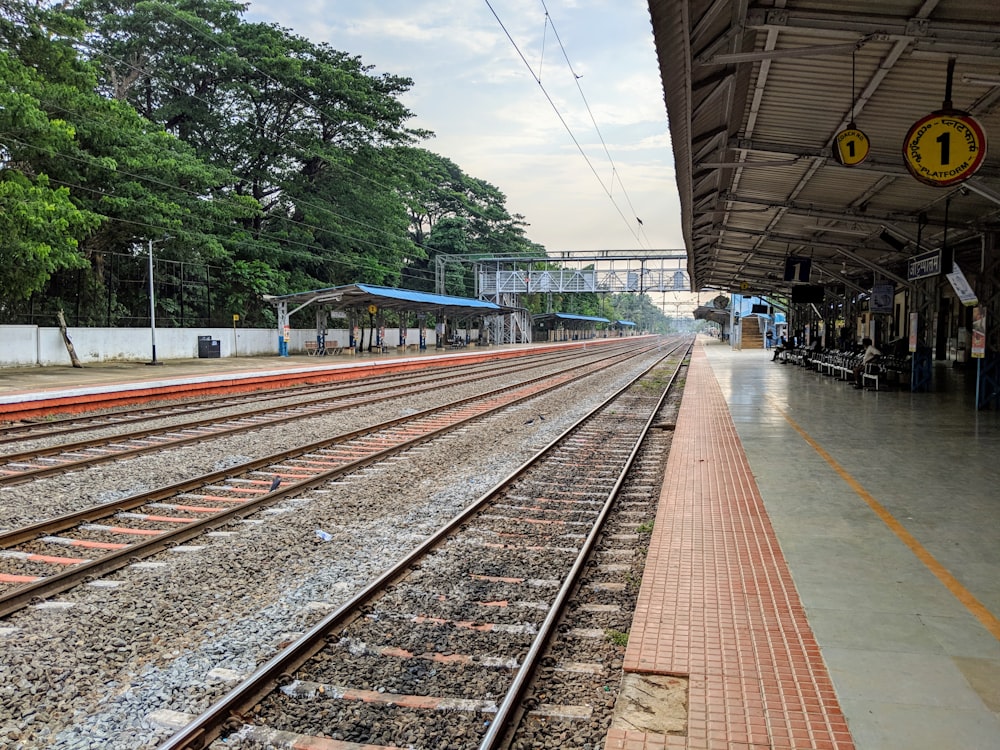 train rail near green trees during daytime