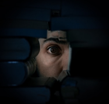 A human eye peering through a gap between stacked books, creating a sense of mystery and curiosity.