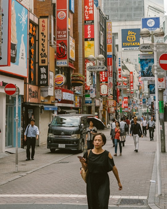 man in black crew neck t-shirt walking on sidewalk during daytime in Shibuya Japan