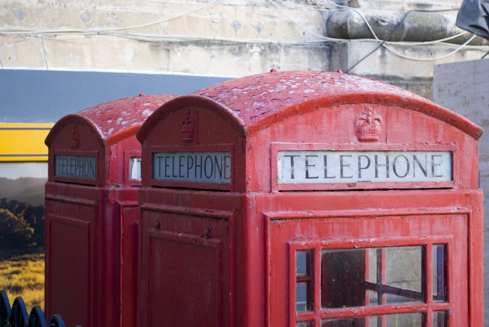 red telephone booth near gray concrete building during daytime