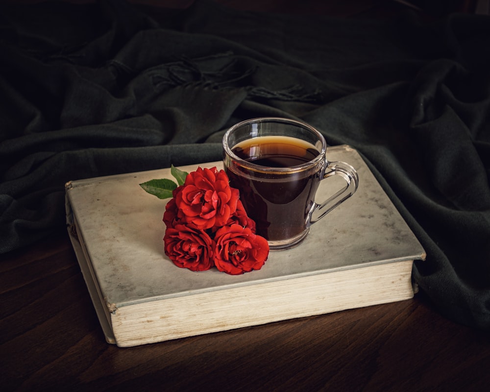 red rose on clear glass mug on brown wooden table