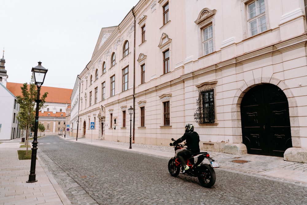 black motorcycle parked beside beige concrete building during daytime