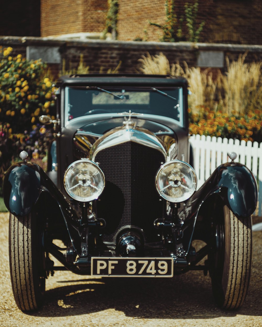 blue vintage car near white wooden fence during daytime