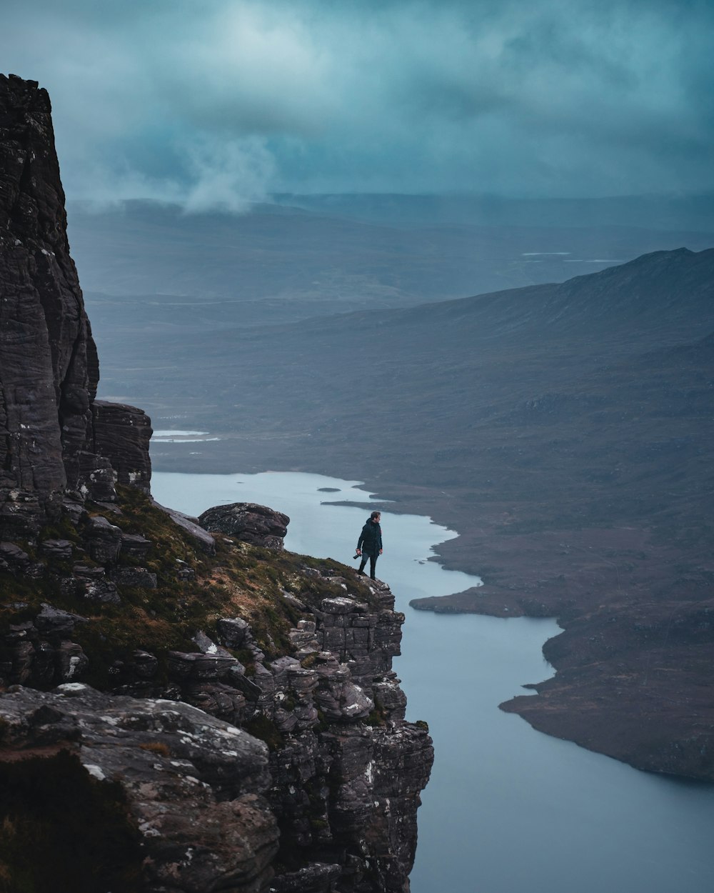 person standing on rock formation near body of water during daytime