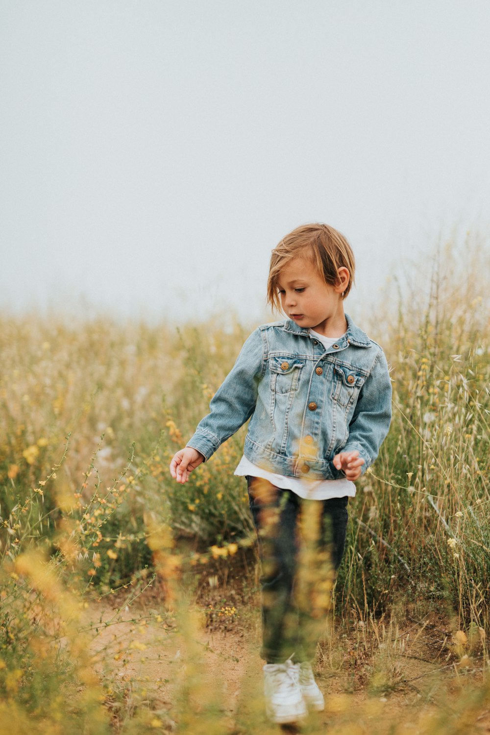 girl in blue denim jacket standing on green grass field during daytime