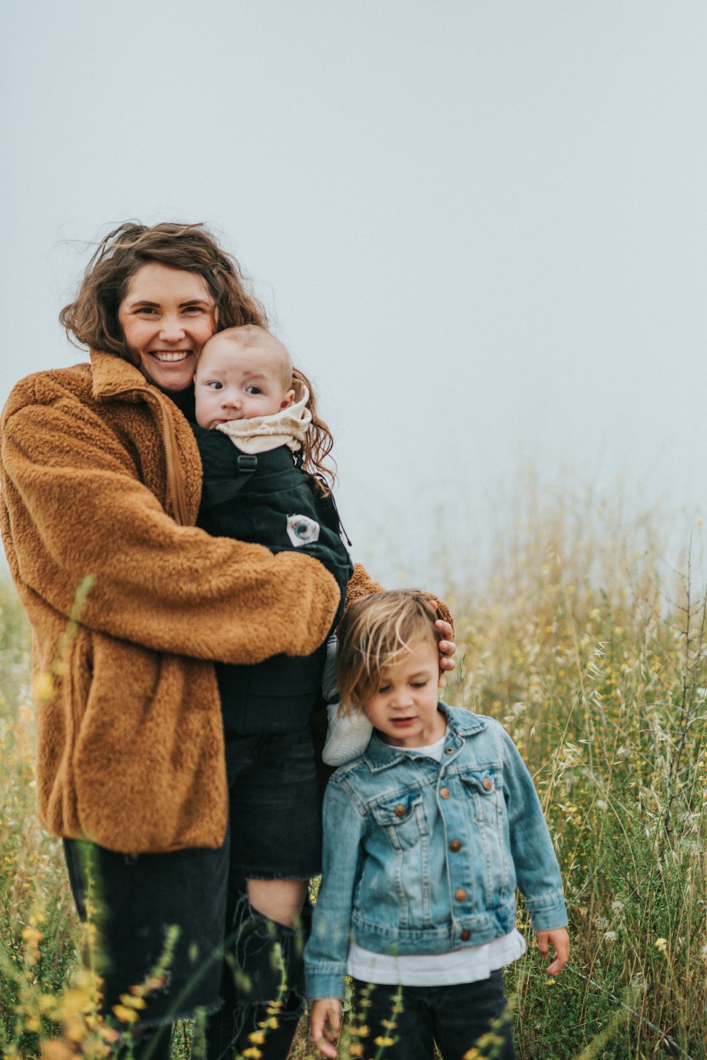 girl in blue denim jacket carrying girl in brown coat