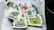 A collection of cartoonish and vibrant stickers featuring various humorous and playful characters, including a caveman with a cigar, smiling green creatures, and quirky designs. Each sticker is colorful and arranged in a casual, overlapping manner on a surface.
