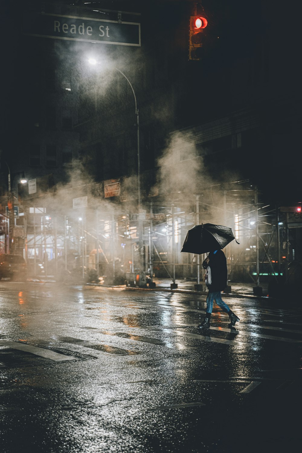person in black jacket holding umbrella walking on street during rainy day