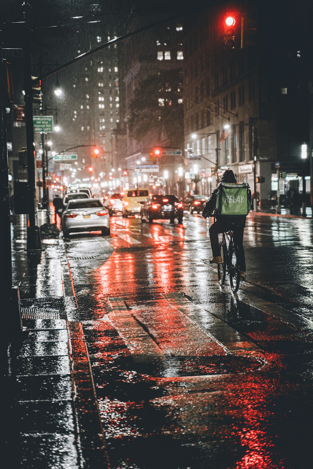 Hombre con chaqueta verde y pantalones negros caminando por la calle durante la noche