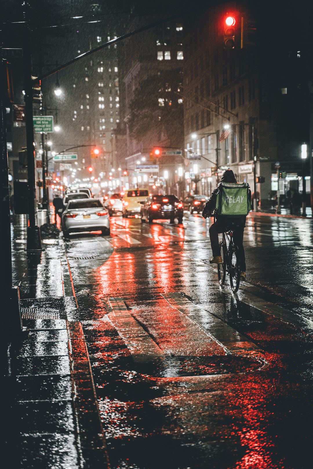 man in green jacket and black pants walking on street during night time