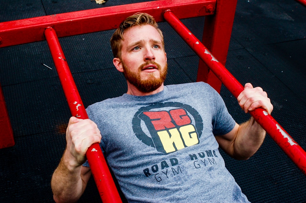man in gray crew neck t-shirt holding red metal bar