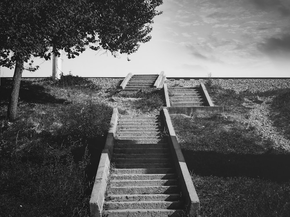 grayscale photo of concrete stairs near body of water