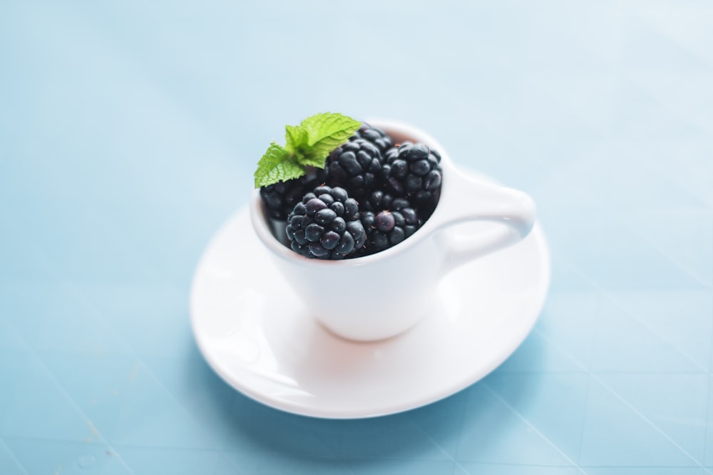 black berries in white ceramic cup on white saucer