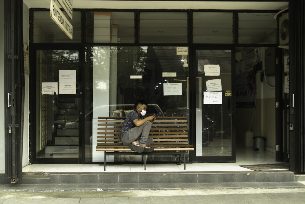 man in black t-shirt sitting on brown wooden bench