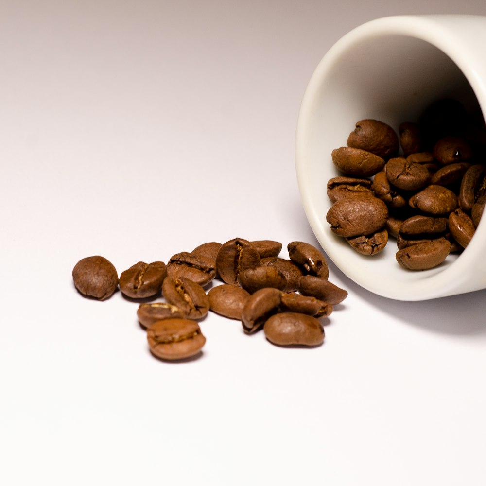 brown coffee beans on white ceramic mug