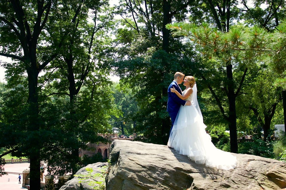 woman in white wedding dress standing on brown rock during daytime