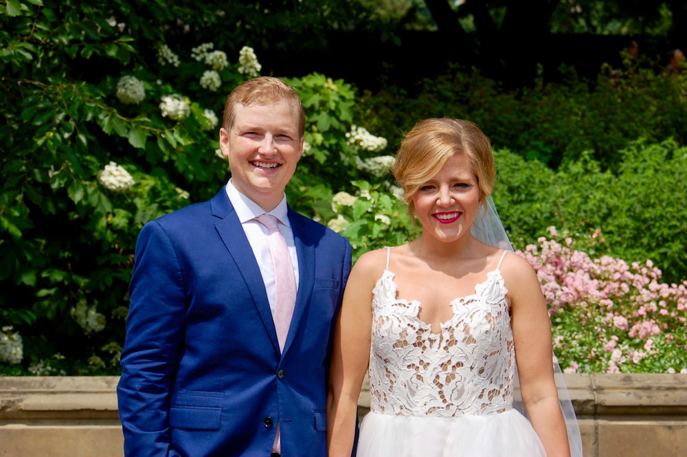 man in blue suit jacket beside woman in white floral lace sleeveless dress