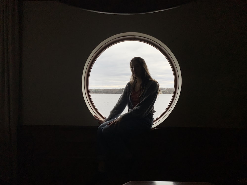 woman in white long sleeve shirt sitting on window