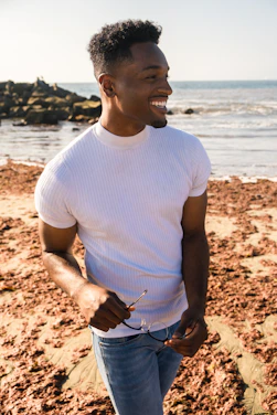 A happy person wearing trendy sunglasses on a sunny day by the beach.