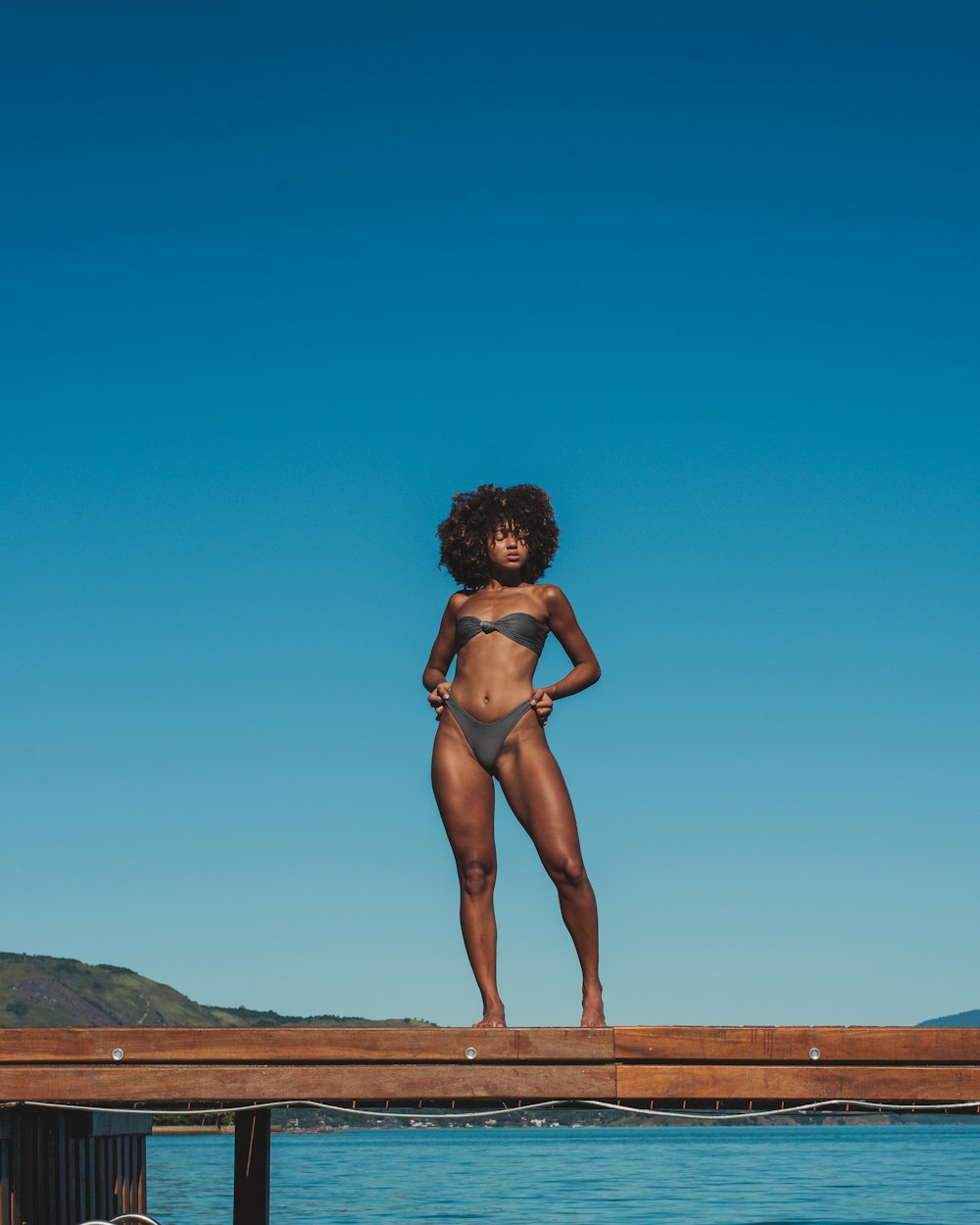 woman in black bikini standing on brown sand during daytime