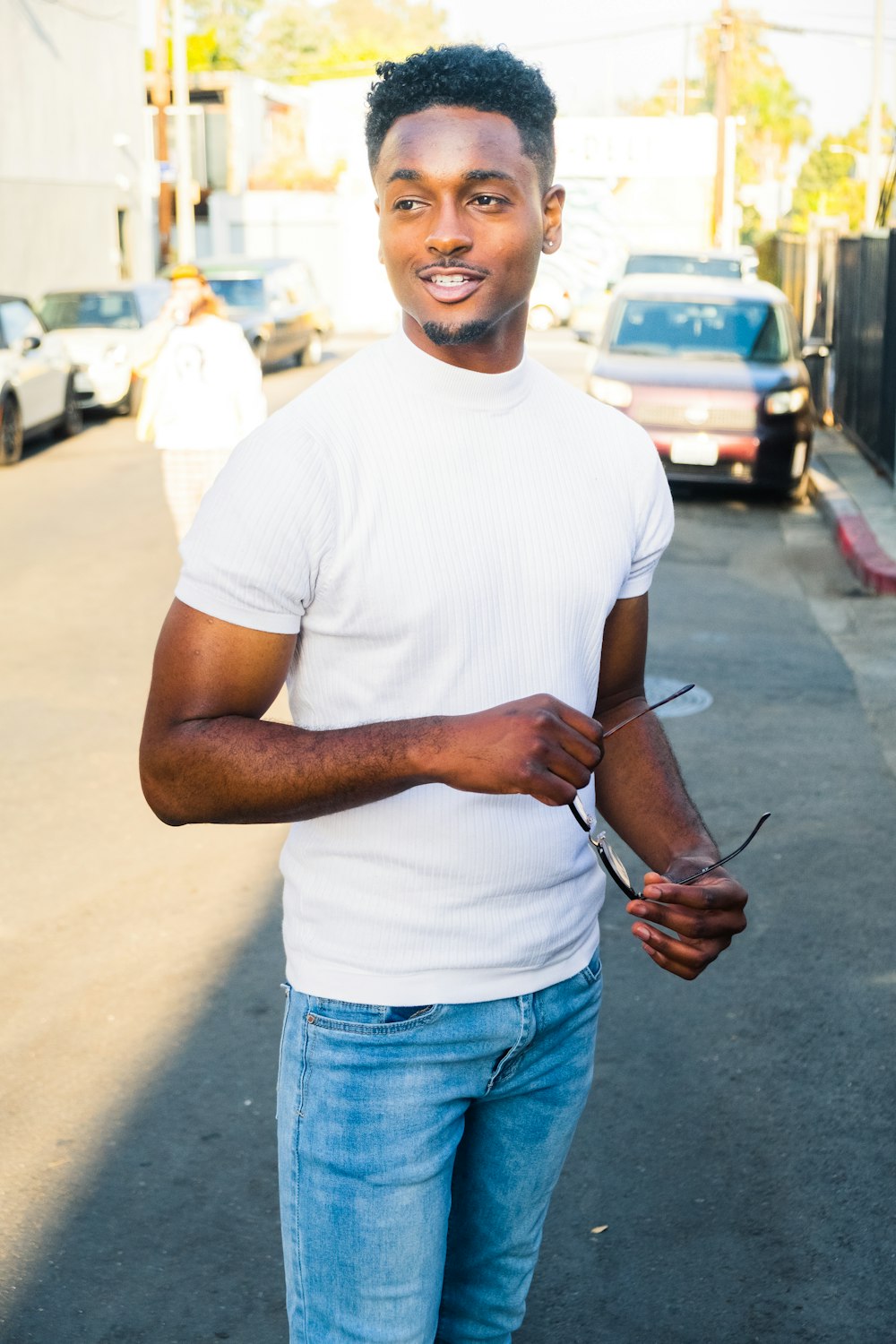 Man in white crew neck t-shirt and blue denim jeans standing on sidewalk  during daytime photo – Free Usa Image on Unsplash