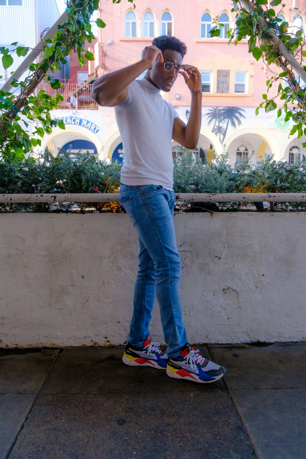 man in white t-shirt and blue denim jeans standing near white wall