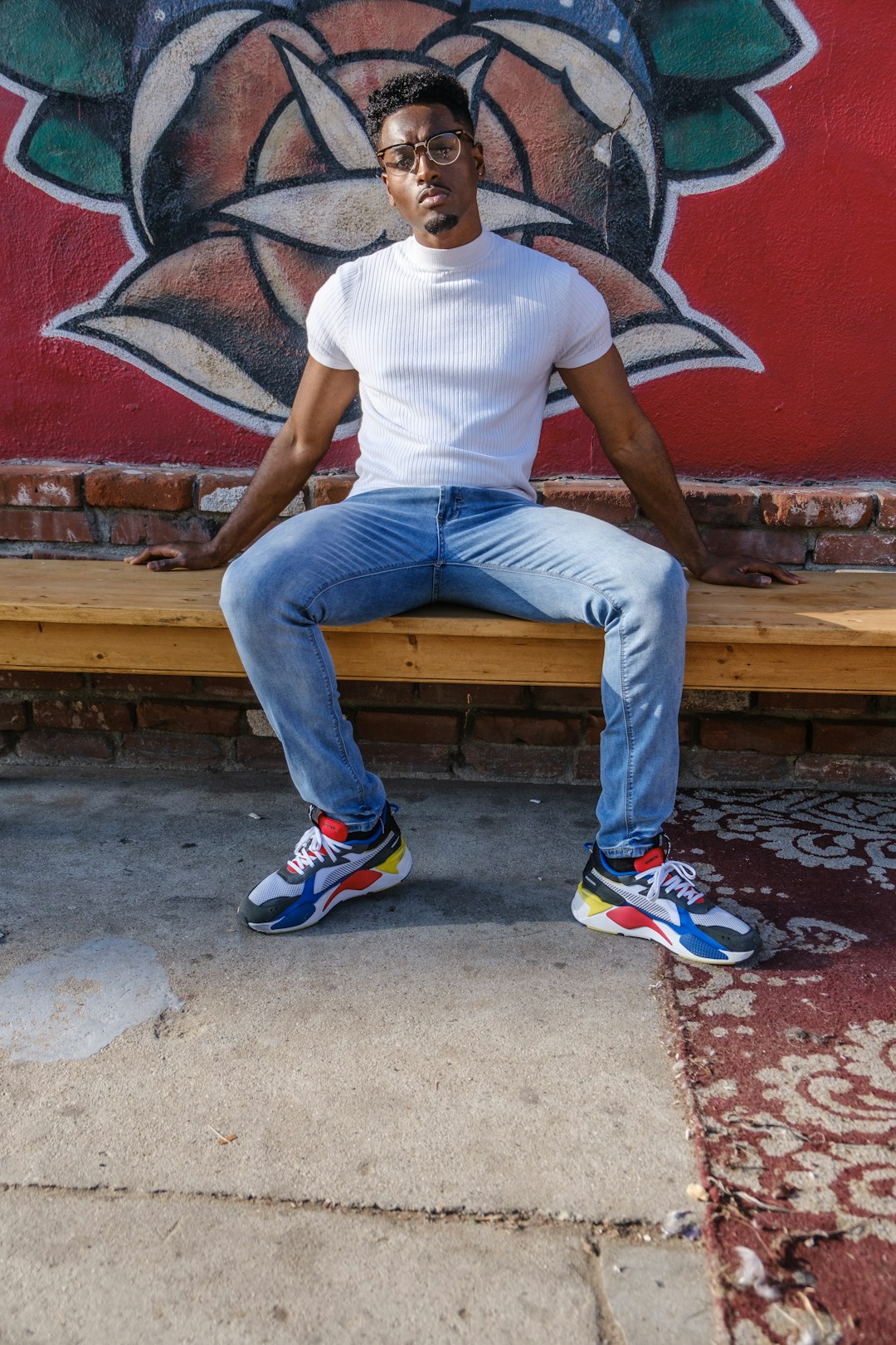 man in white crew neck t-shirt and blue denim jeans sitting on brown wooden bench