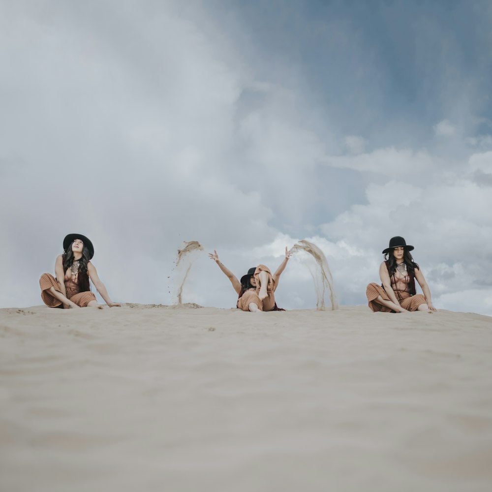 3 women lying on sand during daytime