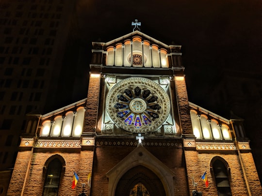 brown and blue concrete building with clock tower during night time in Bucharest Romania